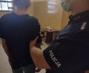 policjanci stoją obok zatrzymanego mężczyzny