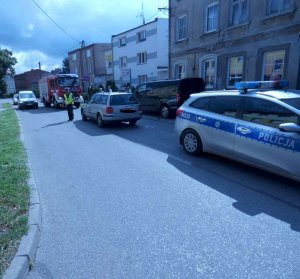 na jezdni stoi radiowóz i pojazdy innych służb. Po jezdni chodzi policjant