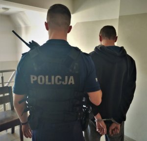 policjant trzyma zatrzymanego mężczyznę