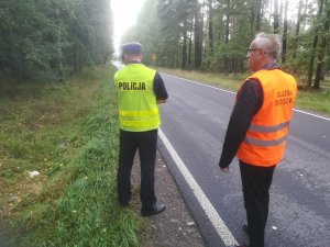 Policjanci na jezdni w tle radiowóz