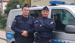 policjanci stoją przy radiowozie