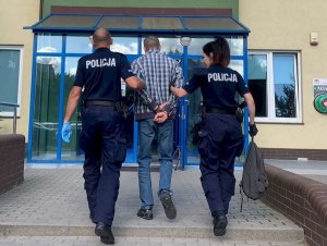 Policjanci prowadzą zatrzymanego