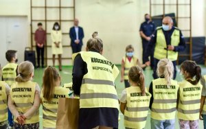 policjanci spotkali się z dziećmi w szkole i rozdają im kamizelki odblaskowe