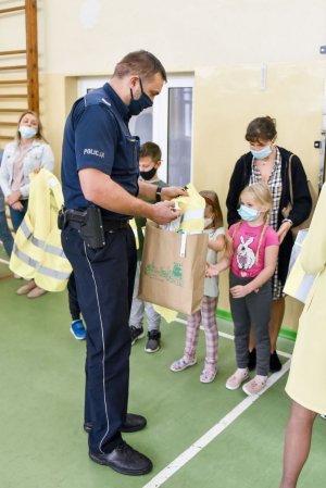 policjanci spotkali się z dziećmi w szkole i rozdają im kamizelki odblaskowe