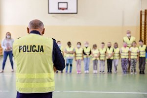 policjanci spotkali się z dziećmi w szkole i rozdają im kamizelki odblaskowe