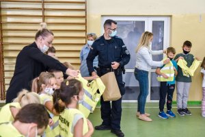 policjanci spotkali się z dziećmi w szkole i rozdają im kamizelki odblaskowe