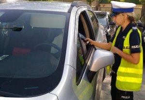 policjantka sprawdza trzeźwość kierowcy, który siedzi w samochodzie