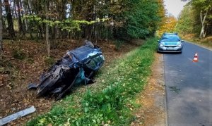 samochód leży w rowie, na zdjęciu widać też oznakowany radiowóz Policji