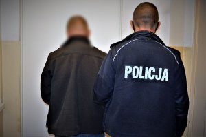 policjant stoi obok zatrzymanego mężczyzny