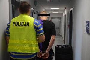 policjant prowadzi zatrzymanego