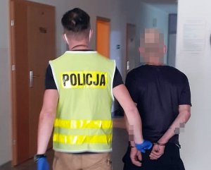 policjant prowadzi zatrzymanego