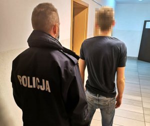 policjant stoi za zatrzymanym mężczyzną