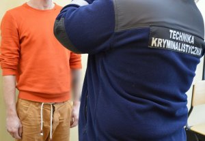 policjant stoi przy zatrzymanym mężczyźnie