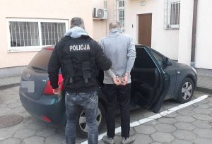 policjant wprowadza do radiowozu zatrzymanego mężczyznę