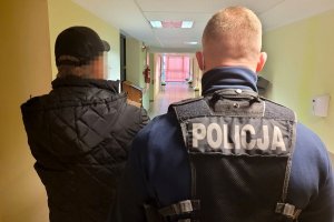 policjant stoi za zatrzymanym mężczyzną