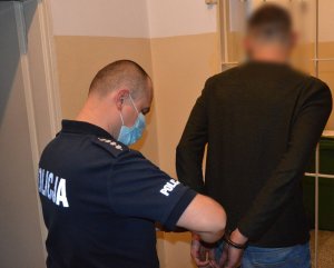 policjant zakłada zatrzymanemu kajdanki