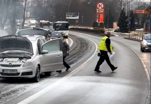 policjanci pomagają ugasić płonące auto