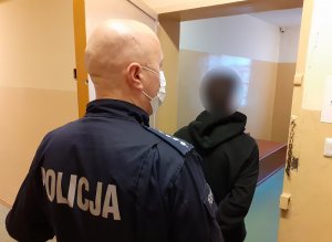 zatrzymany stoi w PDOZ, a za nim stoi policjant