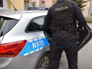 policjant stoi przy radiowozie