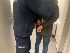 policjant stoi przy zatrzymanym mężczyźnie