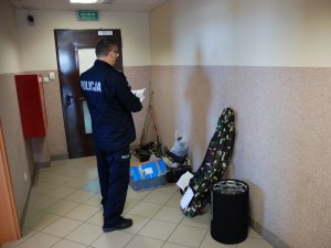 policjant wykonuje oględziny odzyskanych ukradzionych wcześniej z garaży rzeczy