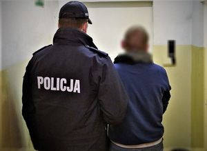 policjant stoi z zatrzymanym mężczyzną