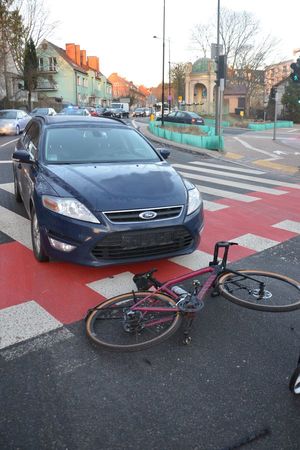 samochód stojący na pasach i leżący na jezdni rower