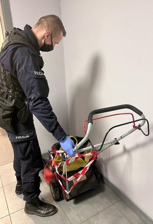 policjant stoi przodem do zabezpieczonej kosiarki