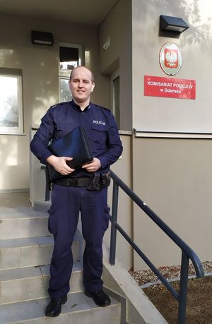 policjant stoi na schodach prowadzących do komisariatu