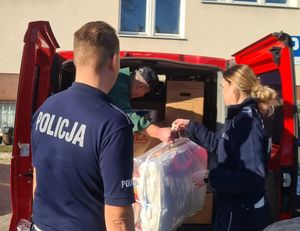 policjanci stoją przy samochodzie z zebranymi darami