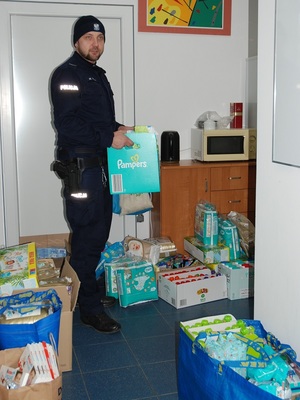 policjant stoi przy darach dla  uchodźców