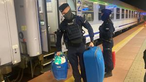 policjanci pomagają wysiąść uchodźcom z pociągu i niosą ich bagaże