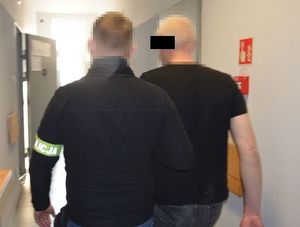 policjant prowadzi zatrzymanego