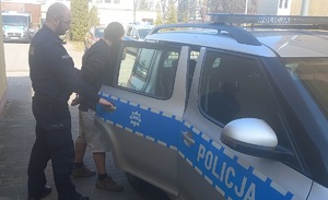 policjant wprowadza zatrzymanego do radiowozu