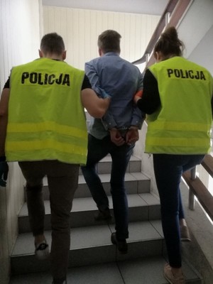 policjanci prowadzą po schodach zatrzymanego