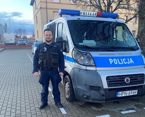 policjant stoi przy radiowozie