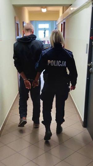 policjant prowadzi zatrzymanego