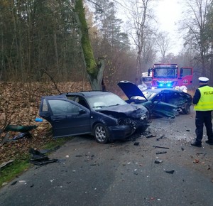 widok rozbitych pojazdów i pracujących na miejscu zdarzenia policjantów