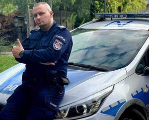 policjant stojący przy radiowozie