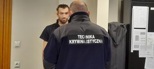 policjant stoi przy zatrzymanym mężczyźnie