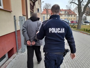 policjant prowadzi  zatrzymanego