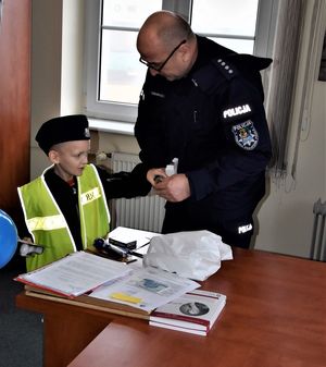 chory chłopiec odwiedził policjantów, zwiedza komendę, siedzi