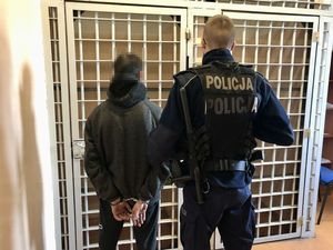 policjant stoi przed celą z zatrzymanym