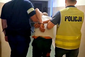 Policjanci prowadzą zatrzymanego mężczyznę.