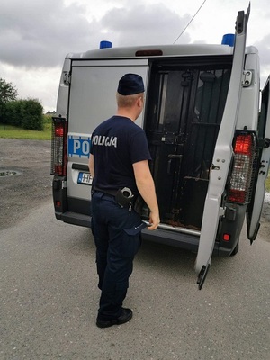 policjant stoi przy radiowozie