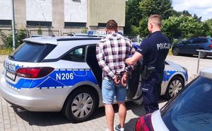 policjant prowadzi zatrzymanego do radiowozu