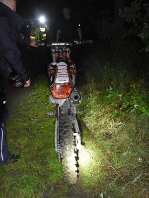 przewrócony na drodze motocykl w tle stojący policjant