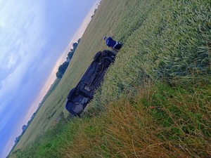 leżące na dachu auto obok stoi policjant