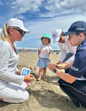 policjanci zakładają dzieciom na plaży opaski niezgubki