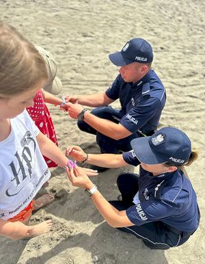 policjanci zakładają dzieciom na plaży opaski niezgubki